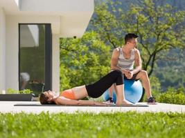 mulher e personal trainer fazendo exercício com bola de pilates foto