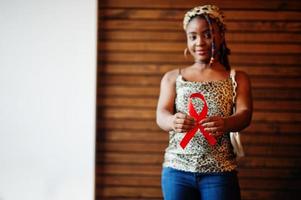 auxilia a conscientização. elegante mulher afro-americana segura fita vermelha. foto