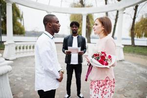 cerimônia de noivado de casamento com o pastor. feliz casal multiétnico na história de amor. relacionamentos de homem africano e mulher branca europeia. foto
