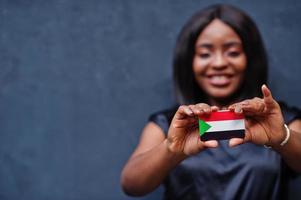 mulher africana segura pequena bandeira do sudão nas mãos. foto