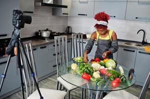 mulher afro-americana filmando sua transmissão de blog sobre comida saudável na cozinha de casa. foto