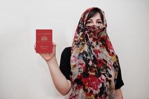 jovem muçulmana árabe em roupas hijab detém passaporte da república da união de mianmar no fundo da parede branca, retrato de estúdio. foto