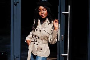 elegante mulher afro-americana usar boina e casaco em pé contra a porta. foto