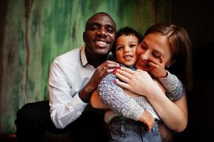 feliz família multiétnica com menino passa tempo no restaurante. relacionamentos de homem africano e mulher branca europeia. foto