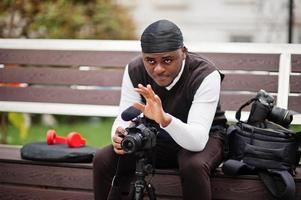 jovem cinegrafista americano africano profissional segurando câmera profissional com equipamento profissional. cinegrafista afro vestindo duraq preto fazendo vídeos. foto