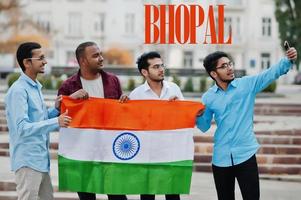 inscrição da cidade de bhopal. grupo de quatro amigos indianos do sexo masculino com bandeira da índia fazendo selfie no celular. maior conceito de cidades da índia. foto