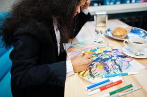 artista indiana mulher vestir imagem de pintura formal e ouvir música hindu de fones de ouvido, enquanto está sentado no café. foto