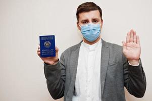 homem europeu com roupa formal e máscara facial, mostre o passaporte da bielorrússia com a mão do sinal de stop. bloqueio de coronavírus no conceito de país da europa. foto