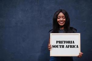 mulher africana segura quadro branco com inscrição de pretoria na áfrica do sul. cidade mais populosa do conceito de áfrica. foto