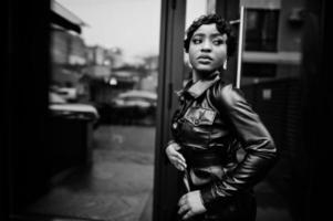 elegante linda mulher afro-americana posando de jaqueta de couro preta na rua. foto