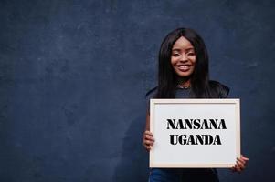 mulher africana segura quadro branco com inscrição nansana uganda. cidade mais populosa do conceito de áfrica. foto