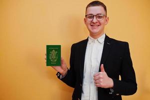 jovem bonito segurando a identificação do passaporte das Ilhas Salomão sobre fundo amarelo, feliz e mostrar o polegar. viajar para o conceito de país da Oceania. foto