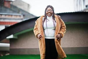 glamourosa mulher afro-americana em pose de casaco de pele quente na rua. foto