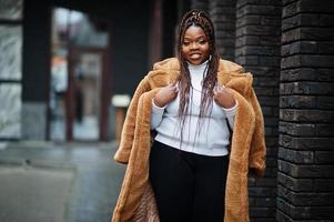 glamourosa mulher afro-americana em pose de casaco de pele quente na rua. foto