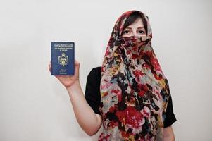 jovem muçulmana árabe em roupas hijab segura passaporte do reino da jordânia hashemita no fundo da parede branca, retrato de estúdio. foto