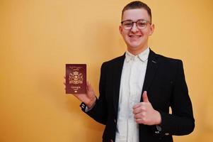 jovem bonito segurando a identificação do passaporte da Geórgia sobre fundo amarelo, feliz e aparecer o polegar. foto