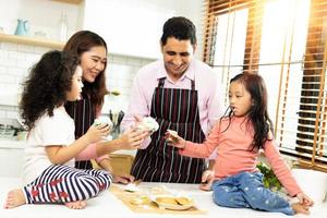 grupo de quatro famílias diversificadas, asiáticas e árabes pré-escolares, crianças árabes africanas fazem bolo cozinhar na cozinha, pai mãe prepara decoração bonita com diversão educar. bagunça de creme no rosto, copie o espaço foto