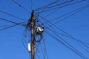 internet, fios e cabos em um poste de distribuição na rua contra o céu azul. foto