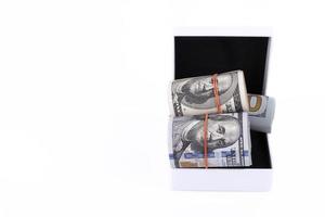 um presente em dinheiro na forma de dinheiro americano rola em uma caixa de presente branca. isolado sobre fundo branco. aproveite seu dinheiro. copie o espaço. foto