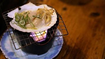 hotate de vieira japonesa fresca com casca na grelha com chamas no restaurante hokkaido, japão foto