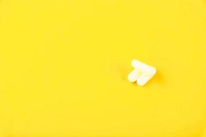 cápsulas brancas, comprimidos em um fundo amarelo. espaço de cópia foto