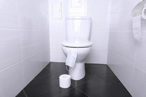 banheiro doméstico branco com papel higiênico de descarga e branco e máscara médica descartável no banheiro. conceito de quarentena. foto