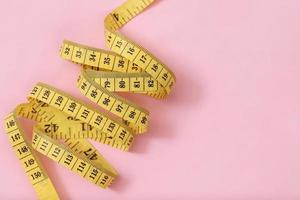 fita métrica para pessoas obesas em um foco suave de fundo rosa foto