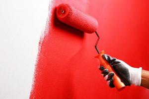pintor está pintando a parede interior de vermelho foto