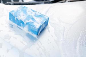 esponja azul e janela de limpador de espuma de bolha para lavar o carro. lavagem de carro de conceito limpa. deixe espaço para escrever mensagens. foto