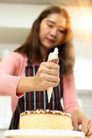 mulher adulta jovem asiática aprende a confeitaria cozinhar bolo on-line curso na cozinha. vídeo de mãe feminina para aula de ciberespaço no laptop como conteúdo de mídia social do blogueiro e aprendizado de streaming, espaço de cópia foto