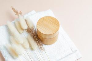 creme facial de colágeno antienvelhecimento em frasco de vidro branco com cana de orelhas secas ou pampas em fundo bege com espaço de cópia. conceito de beleza cosmética orgânica natural. foto