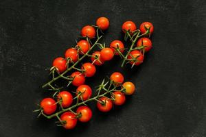 vista superior de tomate cereja fresco em fundo preto. comida saudável, legumes maduros foto