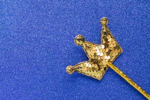 vara mágica dourada de lantejoulas em forma de coroa sobre fundo azul glitter. postura plana criativa de perto foto