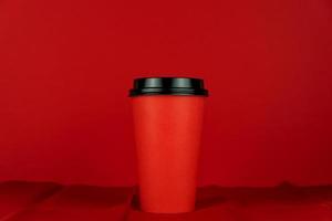 xícara vermelha de café para viagem em um fundo vermelho. foto