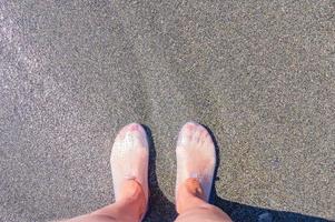 pés femininos em chinelos de borracha protetores para caminhar sobre corais. vista do topo foto