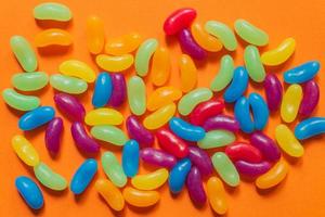 doces de jujubas vitrificadas multicoloridas em fundo de papel laranja foto