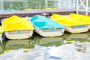 linha de barcos azuis e amarelos estacionados no cais do lago. estação de barcos. estância turística na costa do rio foto