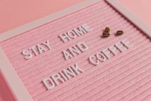 citar ficar em casa e beber café no fundo rosa. trabalhar em casa durante a pandemia de coronavírus. conceito freelance. foto