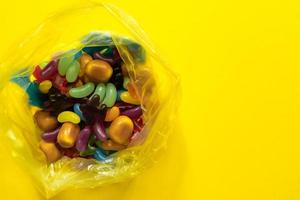 doces de jujubas vitrificadas multicoloridas em pacote plástico em fundo de papel amarelo foto