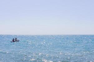 dois homens nadando em uma prancha longa no mar ou oceano em um dia ensolarado. conceito de surf e férias. foto