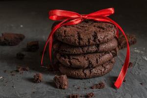 preso de biscoitos de brownie de chocolate com fita vermelha em fundo preto de concreto foto