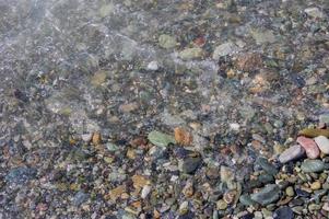 litoral de seixos. beira-mar com água transparente e pequenas pedras foto