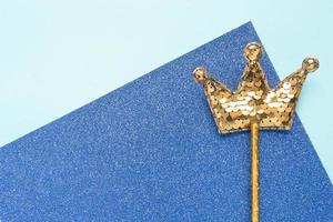 vara mágica dourada de lantejoulas em forma de coroa sobre fundo azul glitter. cama plana criativa de perto foto