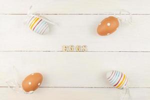 ovos de páscoa em fundo de madeira. ovos de páscoa listrados e pontilhados espalhados em uma mesa foto