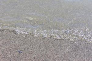 litoral de seixos. beira-mar com água transparente e pequenas pedras foto