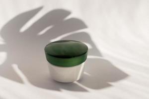 maquete em branco branca do recipiente de creme de garrafa com copo verde. sombras de monstros. tubos profissionais para tratamento facial e corporal. foto