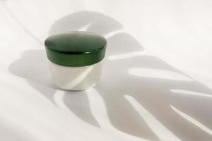 maquete em branco branca do recipiente de creme de garrafa com copo verde. sombras de monstros. tubos profissionais para tratamento facial e corporal. foto