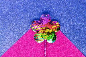 vara mágica de lantejoulas em forma de flor em fundo de glitter azul e rosa. postura plana criativa de perto foto