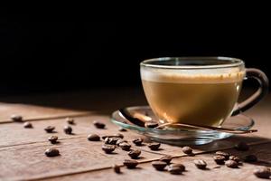 xícara de café quente com leite em um fundo escuro. café com leite ou cappuccino em uma mesa de madeira com espaço de cópia foto