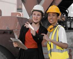 grupo diversificado de pessoas trabalhando juntos no terminal de contêineres. capataz americano africano feminino e gerente de mulher engenheira industrial em pé no depósito de contêineres. conceito de pessoas de negócios de diversidade. foto